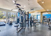Thumbnail 7 of 40 - A spacious gym with a variety of equipment including treadmills, weight machines, and a ceiling fan.