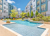 Thumbnail 5 of 40 - A swimming pool in a residential area surrounded by trees and buildings.