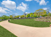 Thumbnail 10 of 40 - A park with a paved pathway and a grassy area.