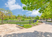 Thumbnail 11 of 40 - A park with a bench and a fence.