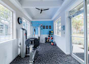 Thumbnail 28 of 51 - A gym room with a rowing machine and a bench.