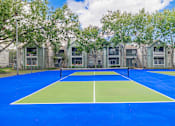 Thumbnail 46 of 51 - A tennis court is surrounded by apartment buildings.