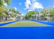 Thumbnail 47 of 51 - A tennis court surrounded by trees and buildings.