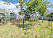 Thumbnail 40 of 51 - A playground with a blue and yellow swing set in front of apartment buildings.