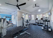 Thumbnail 26 of 51 - A spacious gym with various exercise equipment and a ceiling fan.