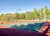 Thumbnail 6 of 22 - a tennis court with a fence and trees in the background