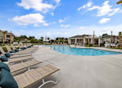 Thumbnail 2 of 26 - A pool area with sun loungers and a clear blue sky.