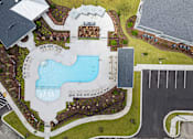 Thumbnail 1 of 26 - A large swimming pool surrounded by a grassy area and a building in the background.