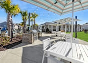 Thumbnail 22 of 26 - A patio with a table and chairs under a striped umbrella.