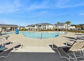 Thumbnail 26 of 26 - A large swimming pool surrounded by lounge chairs and palm trees.