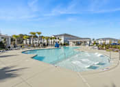 Thumbnail 3 of 26 - A large outdoor swimming pool with a slide and a building in the background.
