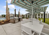 Thumbnail 21 of 26 - A patio with a table and chairs under a striped umbrella.