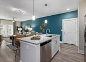 Thumbnail 23 of 26 - A kitchen with a white island and a stainless steel refrigerator.