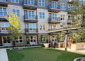 Thumbnail 24 of 27 - A small putting green in front of apartment buildings.