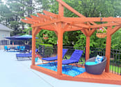Thumbnail 27 of 47 - A wooden pergola with blue chairs and a wicker ottoman.
