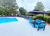 Thumbnail 7 of 47 - A pool with a blue umbrella and chairs.