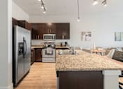 Thumbnail 6 of 20 - A kitchen with a granite countertop and stainless steel appliances.