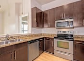 Thumbnail 7 of 20 - A kitchen with brown cabinets and stainless steel appliances.