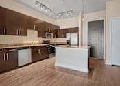 Thumbnail 12 of 20 - A kitchen with brown cabinets and a white island.