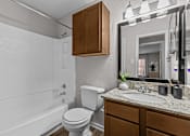 Thumbnail 8 of 32 - A white toilet sits next to a white bathtub in a bathroom.
