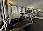 Thumbnail 35 of 36 - a gym with a treadmill and a workout bike in it