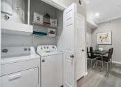 Thumbnail 12 of 32 - a laundry room with a washer and dryer and a dining room table with chairs