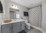 Thumbnail 11 of 32 - a bathroom with gray cabinets and a gray shower curtain