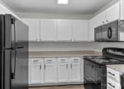 Thumbnail 21 of 29 - a kitchen with white cabinets and black appliances and a refrigerator