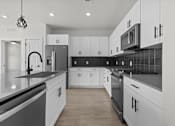 Thumbnail 20 of 24 - A modern kitchen with white cabinets and black countertops.