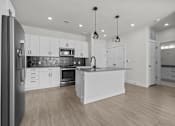 Thumbnail 15 of 24 - A modern kitchen with white cabinets and a wooden floor.