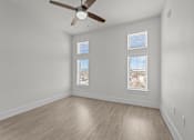 Thumbnail 13 of 24 - A room with a ceiling fan and two windows.