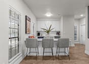 Thumbnail 4 of 30 - A kitchen with a bar area and two grey chairs.
