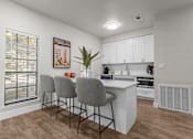 Thumbnail 9 of 30 - A kitchen with white cabinets and a wooden floor.
