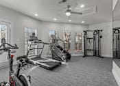 Thumbnail 15 of 30 - A spacious home gym with a treadmill, stationary bike, and weightlifting equipment.