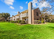 Thumbnail 16 of 30 - A large grassy area in front of a building with a balcony.