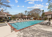 Thumbnail 20 of 30 - A swimming pool surrounded by a concrete patio and lounge chairs.