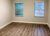 Thumbnail 6 of 19 - an empty bedroom with two windows with wood flooring