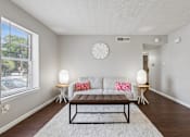 Thumbnail 6 of 22 - A living room with a couch, a table, and a clock on the wall.
