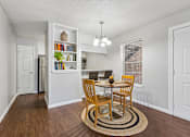 Thumbnail 14 of 22 - A dining room with a table set for two and a bookshelf filled with books.