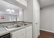 Thumbnail 5 of 22 - A kitchen with a sink and a refrigerator.