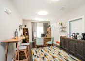 Thumbnail 13 of 17 - a room with a desk and chairs and a colorful rug