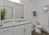 Thumbnail 30 of 41 - A bathroom with a toilet, sink, and mirror.