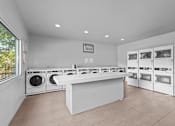 Thumbnail 16 of 22 - a laundry room with a counter and washes and dryers in it