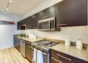 Thumbnail 5 of 19 - A kitchen with a stove top oven and a microwave.