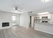 Thumbnail 4 of 19 - A spacious living room with a fireplace and a kitchen area in the background.