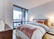 Thumbnail 13 of 19 - A bedroom with a large bed and a view of the city.