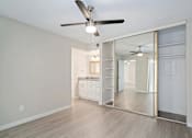 Thumbnail 6 of 19 - A room with a ceiling fan and a mirrored wall.