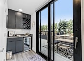 Thumbnail 24 of 35 - A modern kitchen with a view of the backyard through the glass doors.