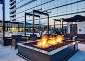 Thumbnail 17 of 19 - A fire pit sits in the middle of a patio with chairs around it.