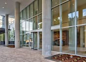 Thumbnail 15 of 19 - A modern building with large glass windows and concrete pillars.
